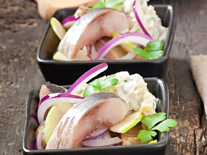 Zwei Schalen mit Matjes und Zwiebelringen auf einem Holztisch