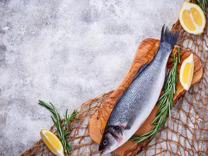 Ganzer Fisch mit Zitrone und Rosmarin auf einem Holzbrett, daneben ein Fischernetz