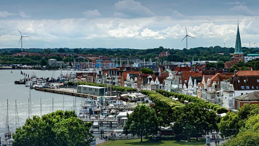 Blick über Travemünde: Sportboothafen an der Trave, dahinter die Häuserzeile der Vorderreihe und der grüne Kirchturm